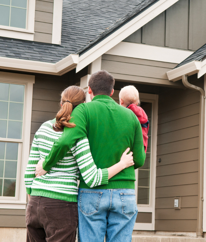 Family standing together outside their new home, facing the front door.