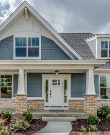 Front view of a modern blue and white house with a covered porch.