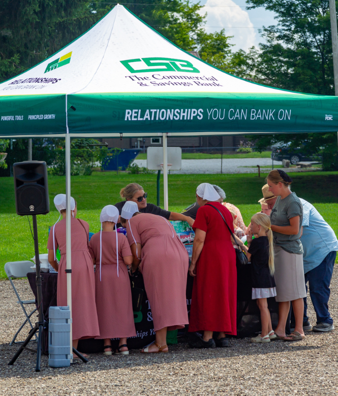 CSB community tent at an outdoor event with people gathered around.